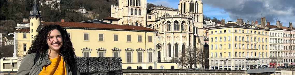 Student standing in front of some yellow European buildings