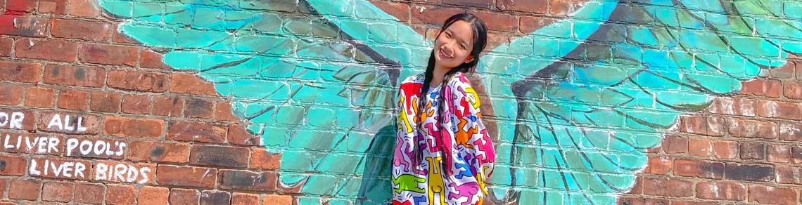 Student standing in front of some painted wings in Liverpool, England