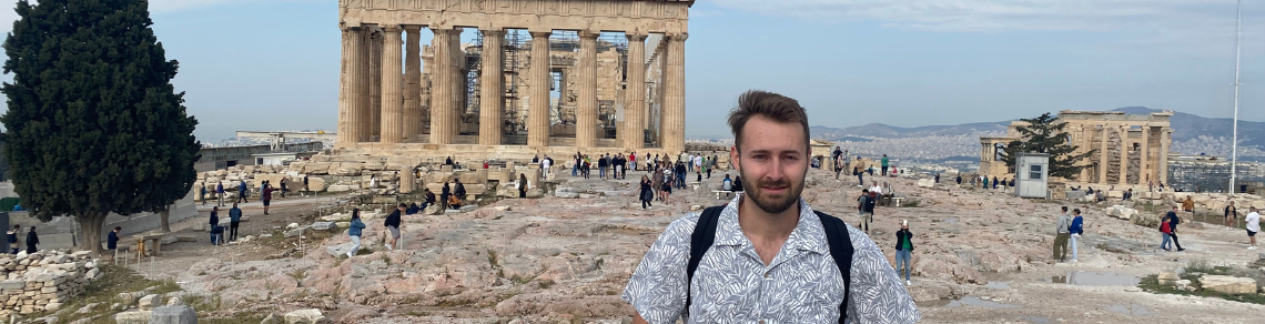 Student standing in fron of the Acropolis, Greece