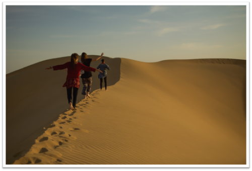 Three students walking along desert dunes
